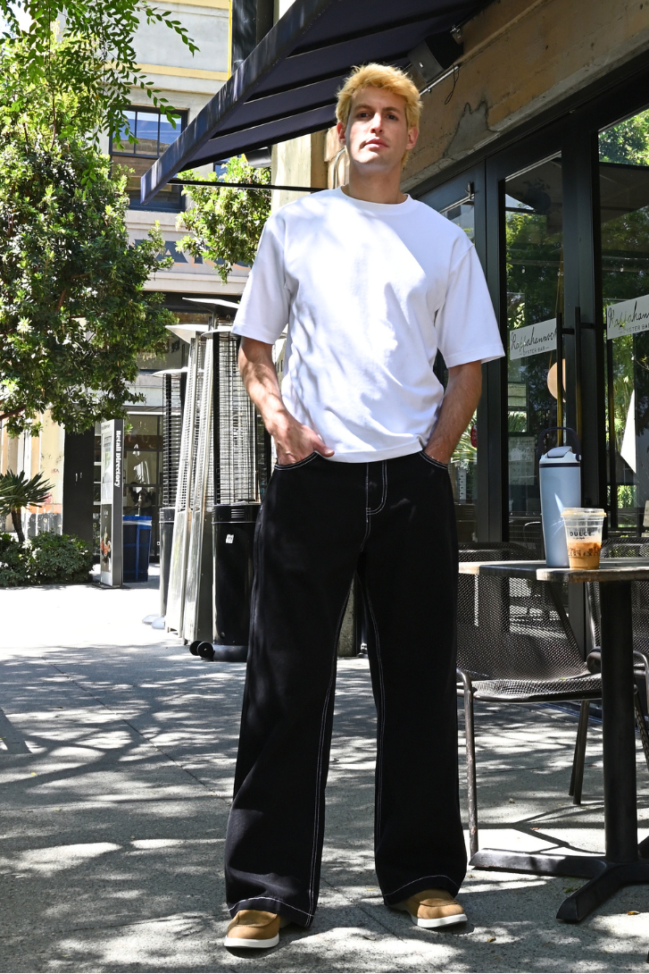 Person standing outside a cafe with tables and chairs